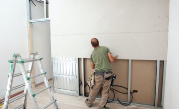 Worker building plasterboard wall.